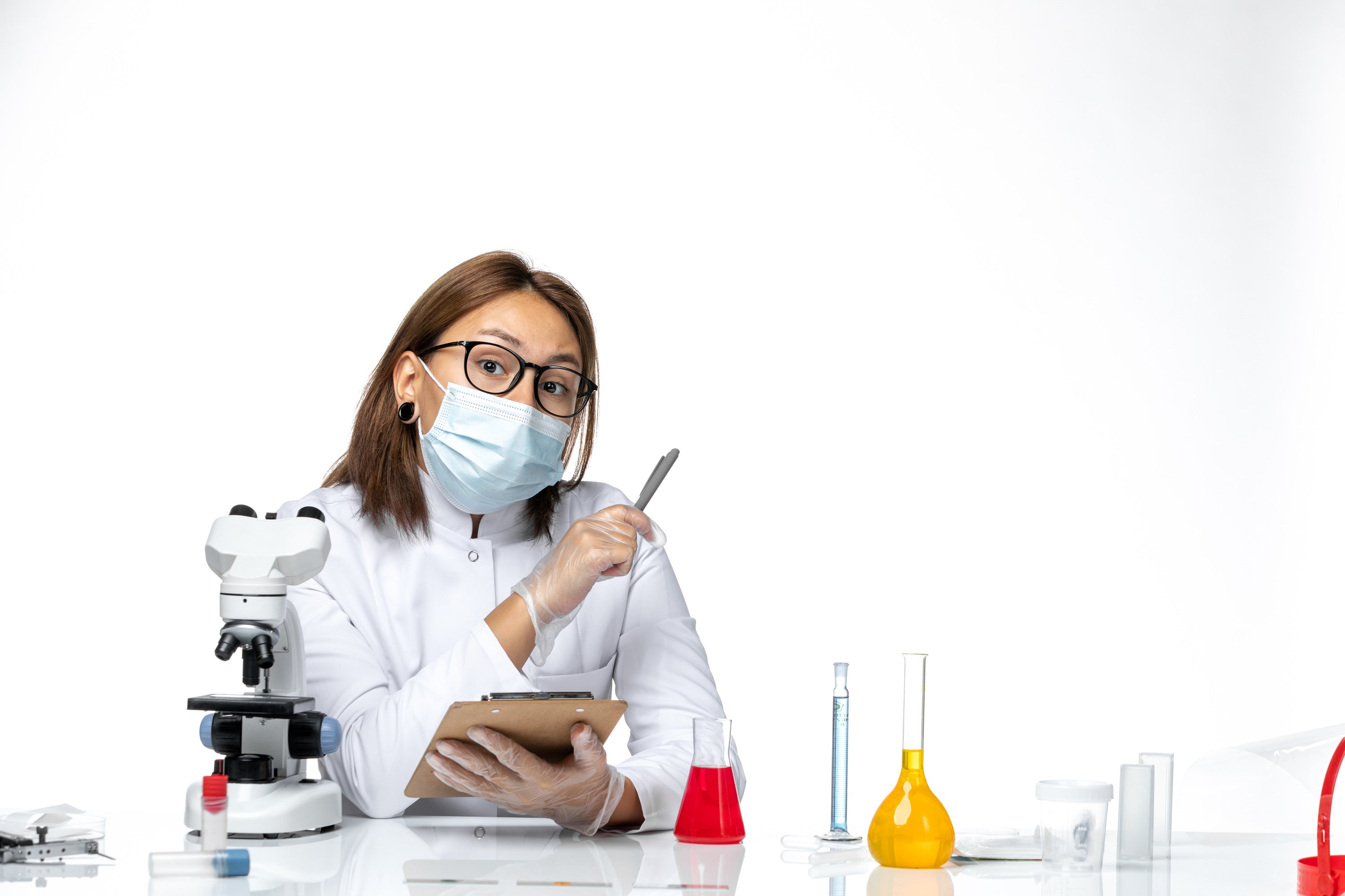 Lab technician wearing mask and gloves, holding test tube during diagnostic testing